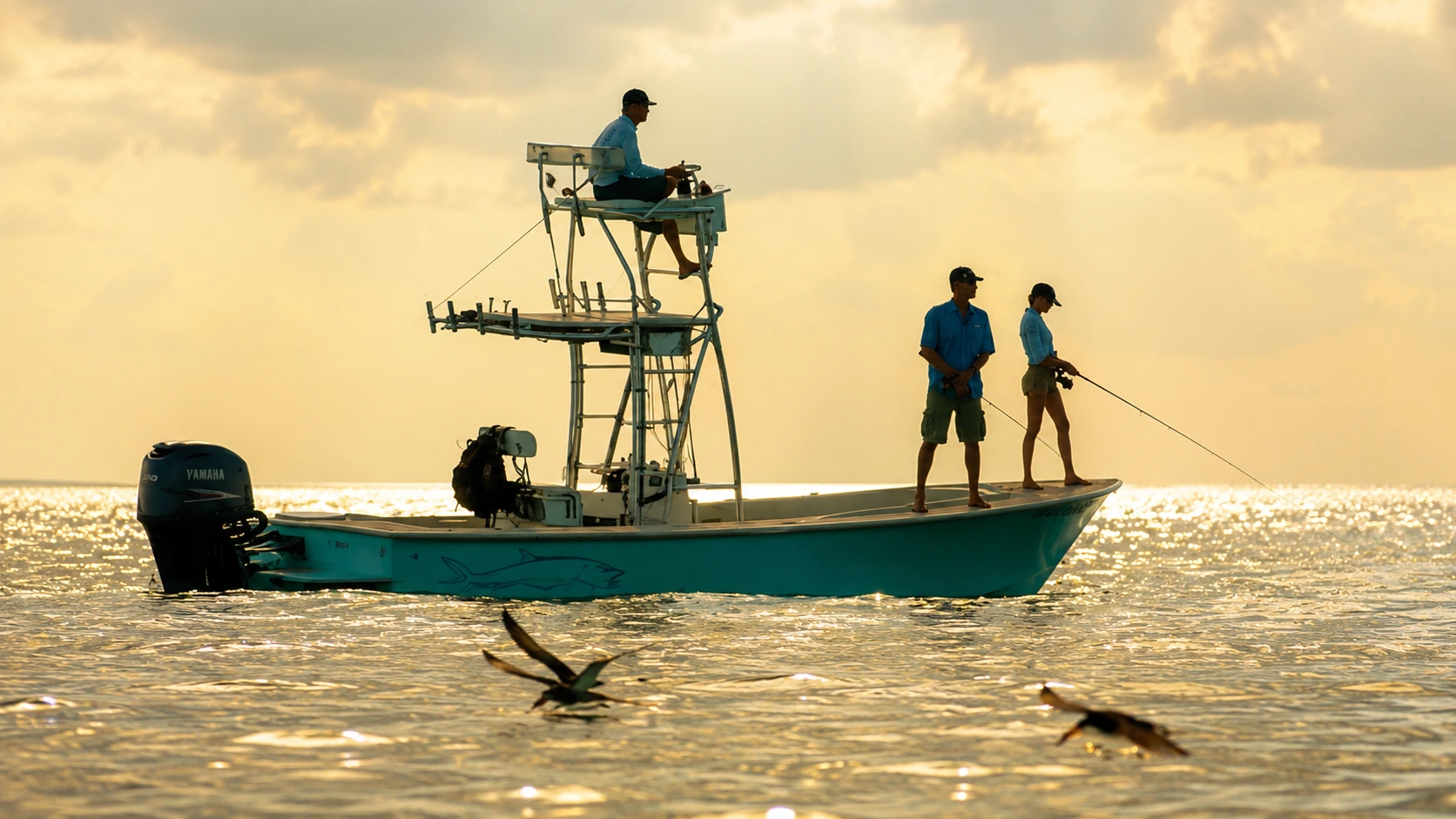 Anglers fly fishing from a technical poling skiff during sunrise on Sarasota Bay.